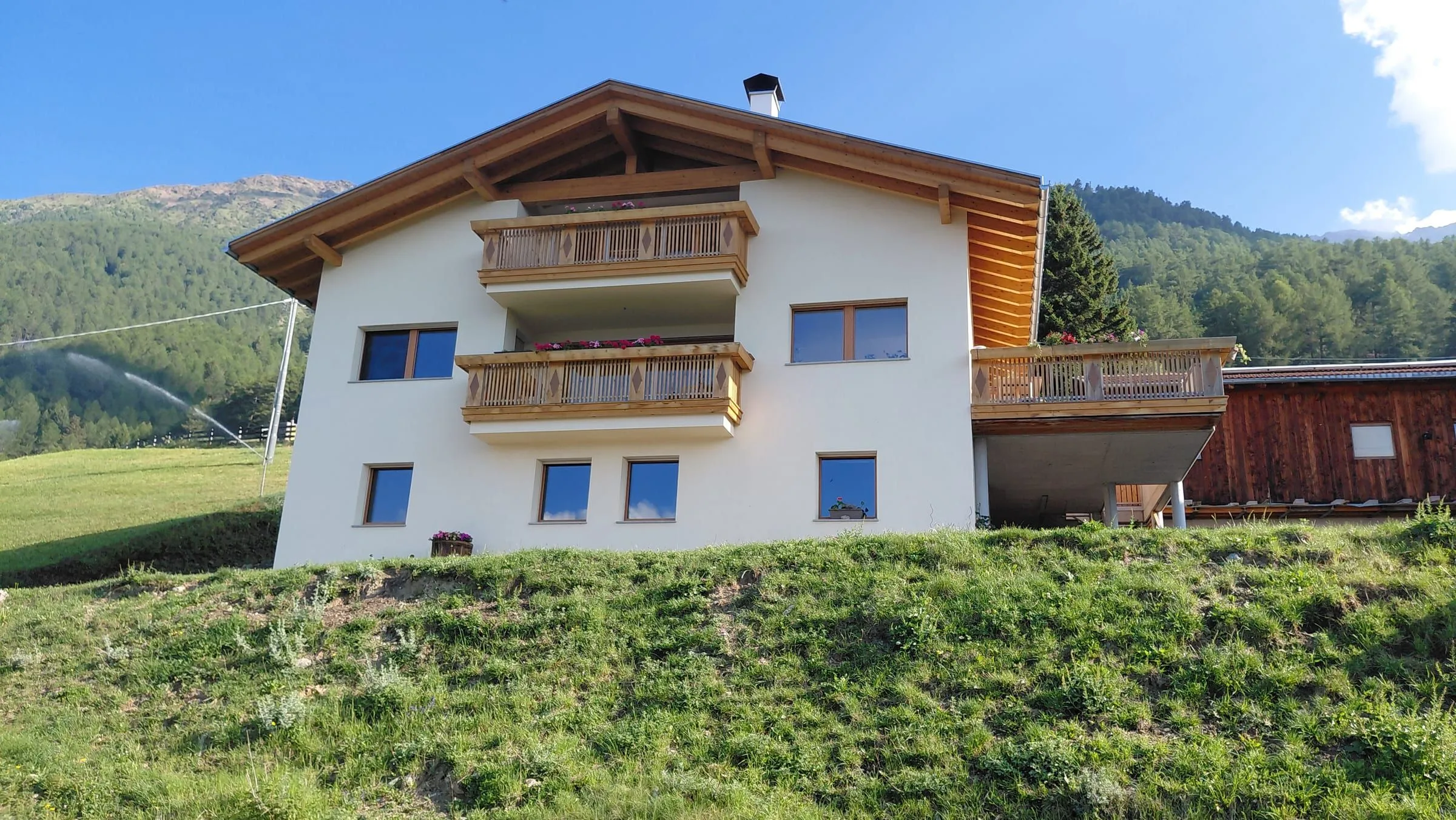Der Frinighof in der Sonne mit Blick auf die Berge
