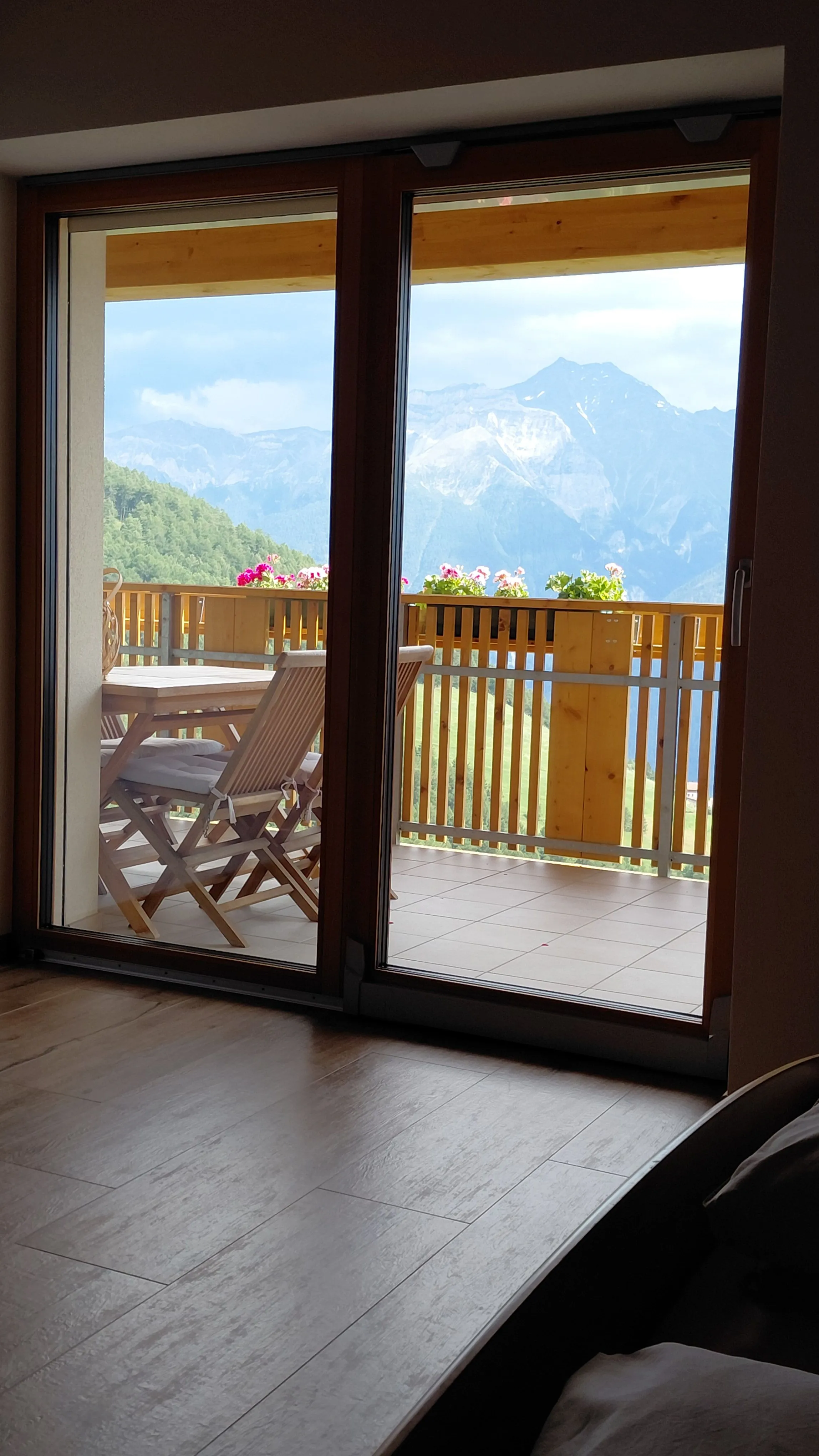 Helles Schlafzimmer der Ferienwohnung mit Holzdecke und Zugang zum Balkon
